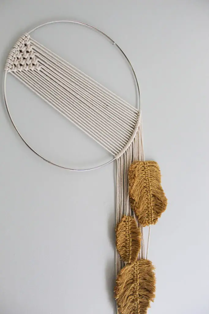 Macrame wall hanging with feathers hanging on the wall.