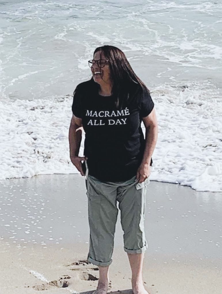 standing on the beach in a t-shirt that says Macrame All Day