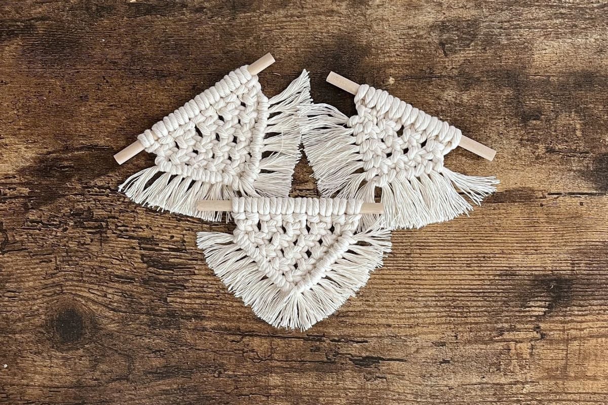 image of set of three macrame Christmas ornament laying on wood table