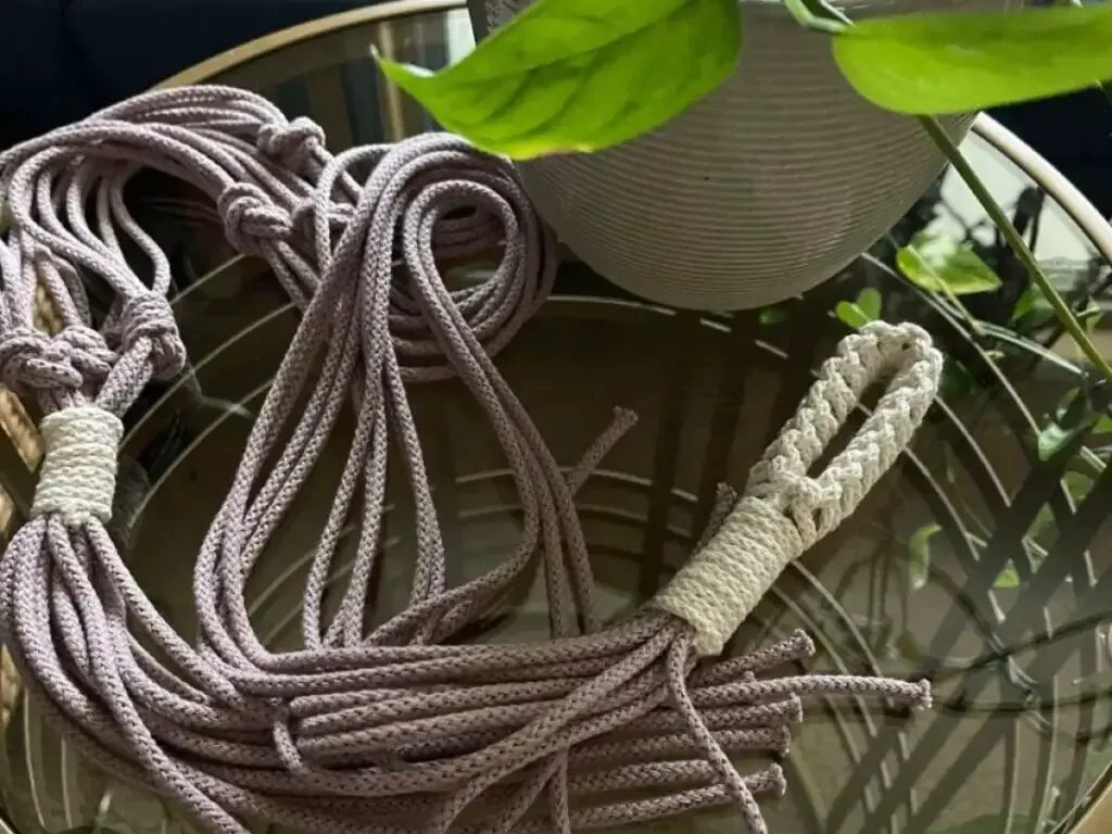 macrame plant hanger made without a ring laying on glass table